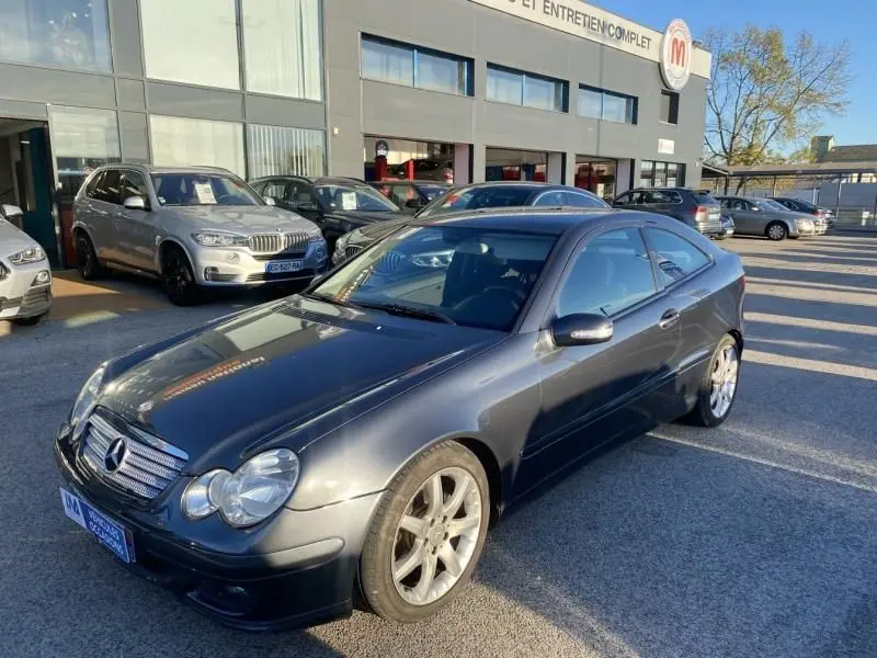 Mercedes Classe C Coupé Sport 220 CDI gris foncé métal vu en 3/4 avant droit sur parking extérieur.