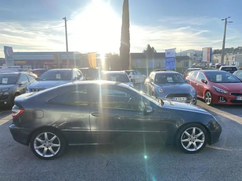 Vue latérale gauche d'une Mercedes Classe C Coupé Sport 220 CDI gris foncé métallisé garée en extérieur au soleil couchant.