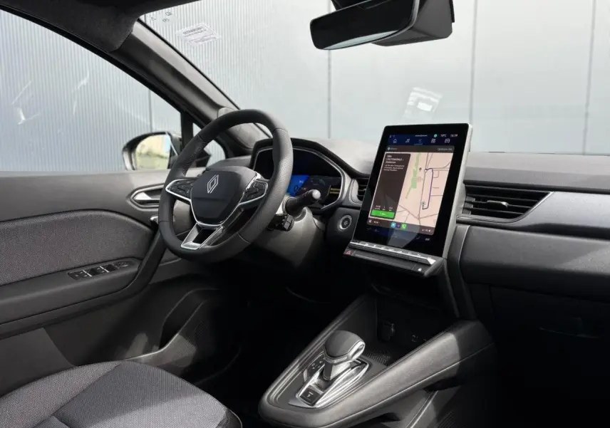 Intérieur de la Renault SYMBIOZ E-Tech 2025, vue côté conducteur, tableau de bord avec écran tactile GPS et volant cuir.