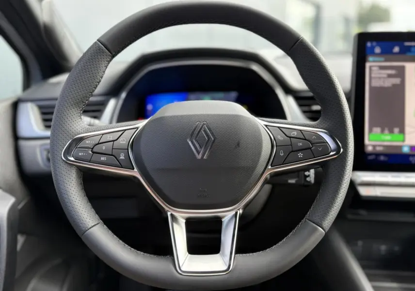 Volant multifonction en cuir avec logo Renault au centre, tableau de bord numérique et écran tactile latéral visibles.