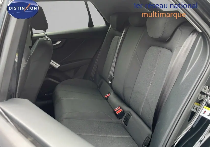 Vue intérieure côté droit montrant la banquette arrière en tissu gris d’un Audi Q2 noir mito metal 2023.