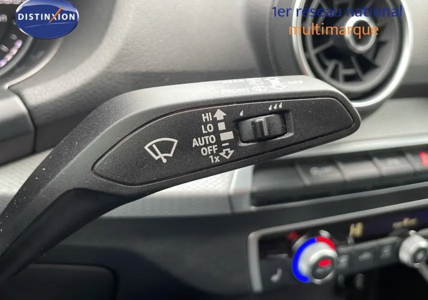 Gros plan sur la commande d’essuie-glace dans l’habitacle d’un Audi Q2 noir, avec tableau de bord et aérateur visibles.