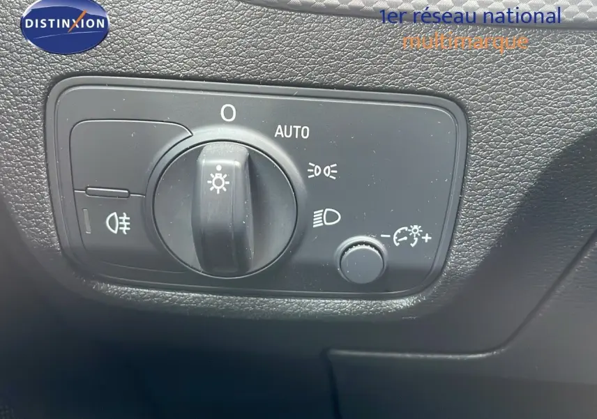 Gros plan sur le bouton de commande des phares de l'Audi Q2 35 TFSI S-Line 2023, intérieur noir texturé.