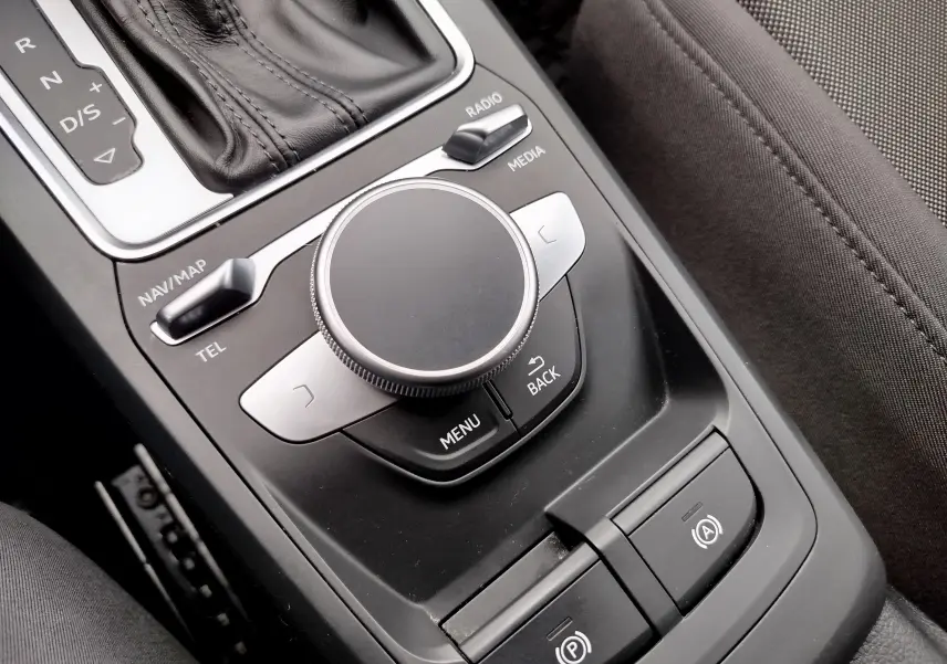 Vue rapprochée de la molette de commande multimédia et levier de vitesse cuir noir dans l'Audi Q2 35 TFSI S-Line 2023.