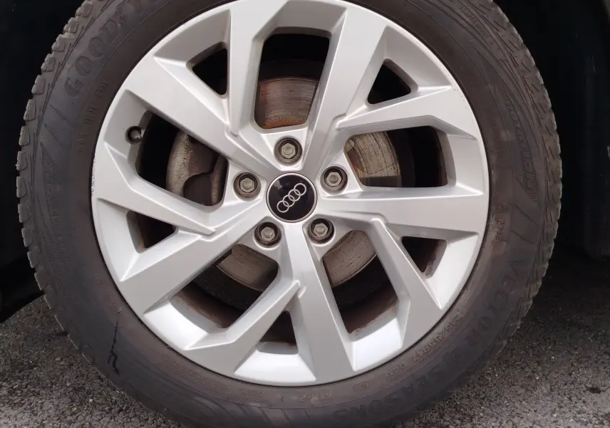 Gros plan sur la jante argentée de l'Audi Q2 noir mito metal, avec logo Audi au centre et pneu Goodyear visible.