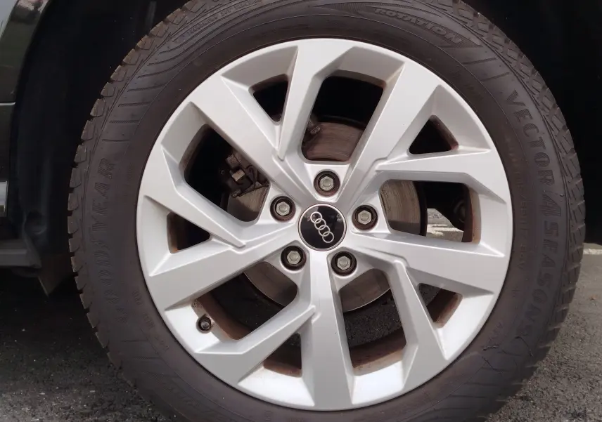 Gros plan sur la jante argentée à cinq branches de l'Audi Q2 noir mito metal, avec logo Audi au centre.