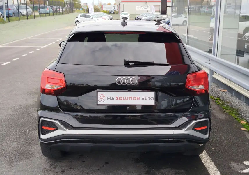 Vue arrière d'un Audi Q2 noir mito metal 2023 avec feux arrière rouges et logo Audi centré sur le hayon.