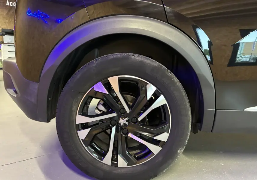 Gros plan sur la roue avant gauche noire du Peugeot 2008 1.5 BlueHDi 130 GT Line avec jante bi-ton distinctive.