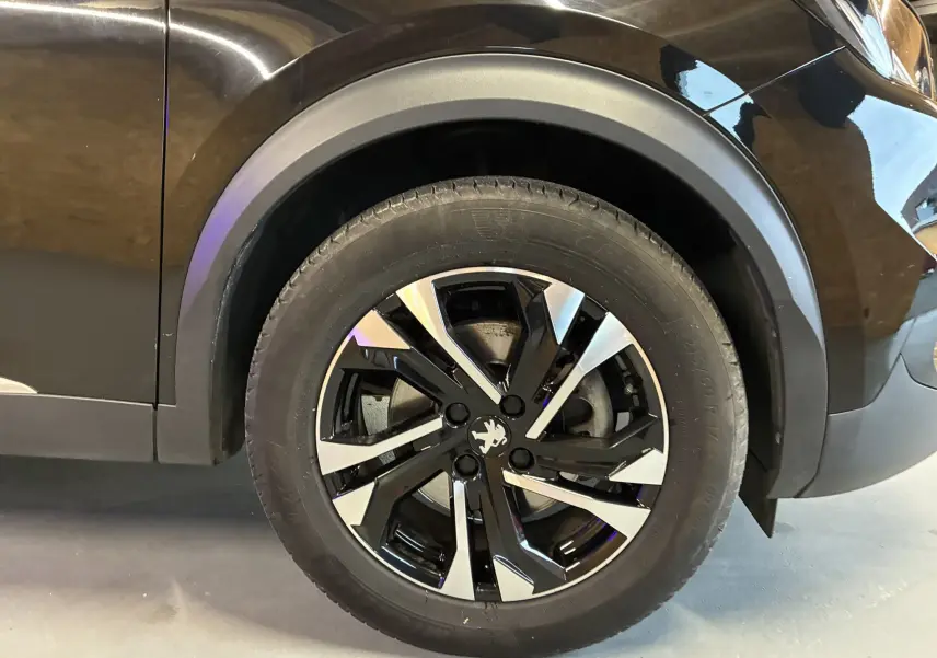 Gros plan sur la roue avant gauche noire du Peugeot 2008 1.5 BlueHDi 130 GT Line avec jante bi-ton distinctive.