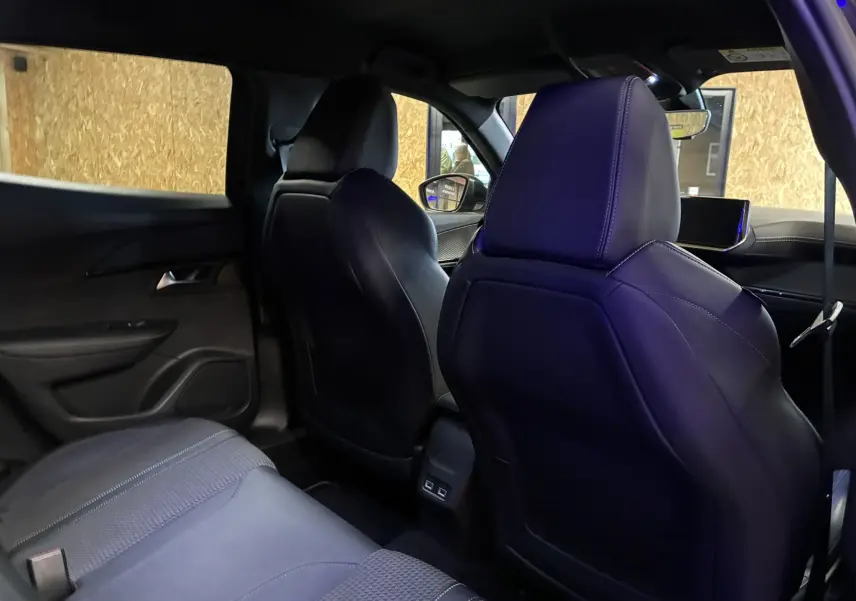 Vue intérieure arrière du Peugeot 2008 noir 2020, montrant les sièges avant en cuir et tissu avec détails couture apparents.