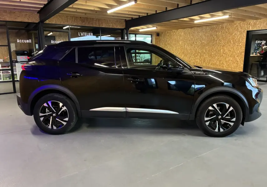 Profil côté gauche d'un Peugeot 2008 noir 2020 GT Line, avec jantes bi-ton et détails chromés sous les portes.