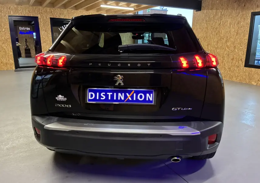 Vue arrière d'un Peugeot 2008 GT Line noir avec feux LED allumés et plaque d'immatriculation Distinxion visible en intérieur.