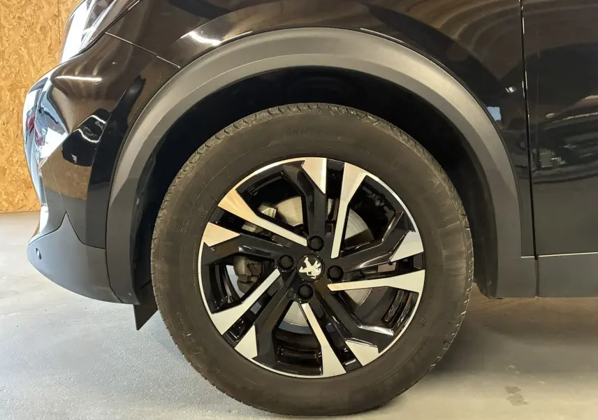 Gros plan sur la roue avant gauche noire d'un Peugeot 2008 GT Line 2020 avec jante bi-ton distinctive.