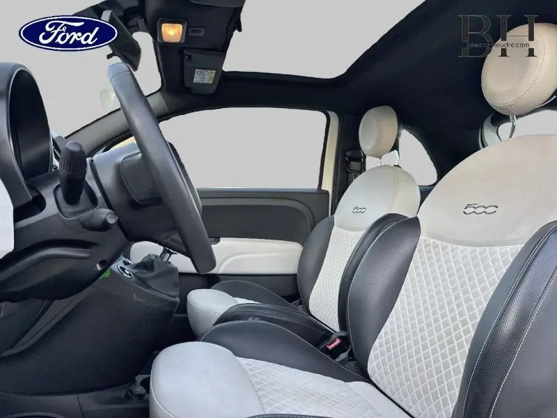 Vue intérieure côté conducteur de la Fiat 500 blanche avec sièges bicolores matelassés et volant cuir multifonction.