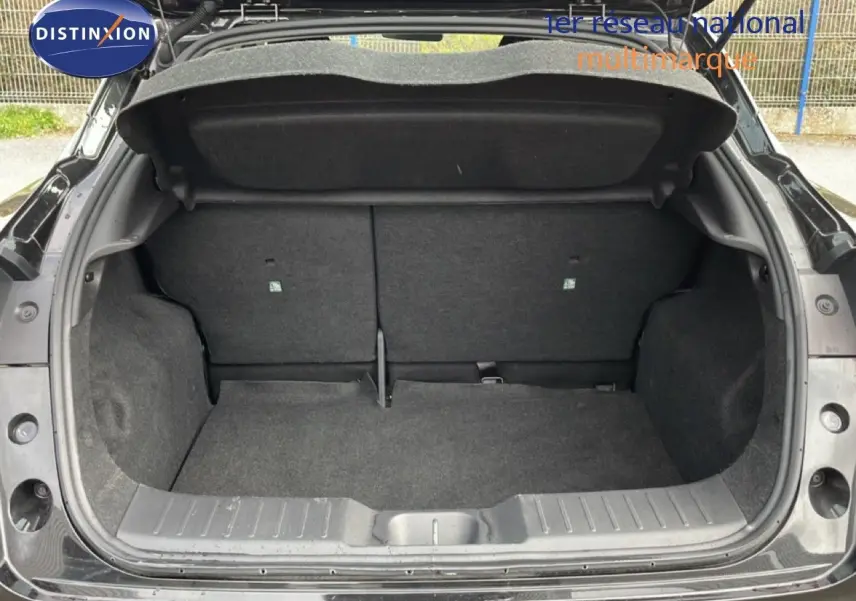Coffre ouvert vu de l'arrière d'un Nissan Juke noir perle métal, montrant l'espace de chargement vide.