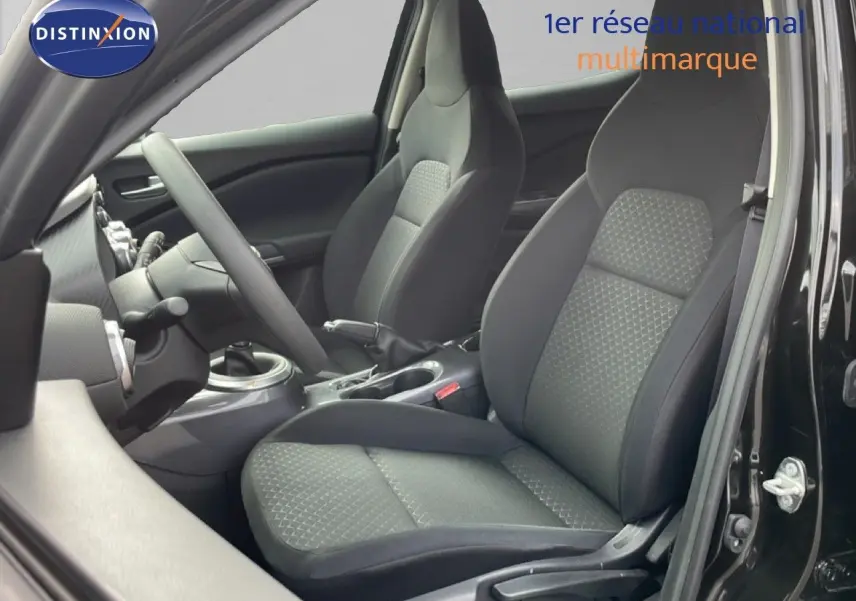 Vue intérieure côté gauche du Nissan Juke noir perle métal 2023, mettant en valeur les sièges en tissu gris noir et la boîte manuelle.