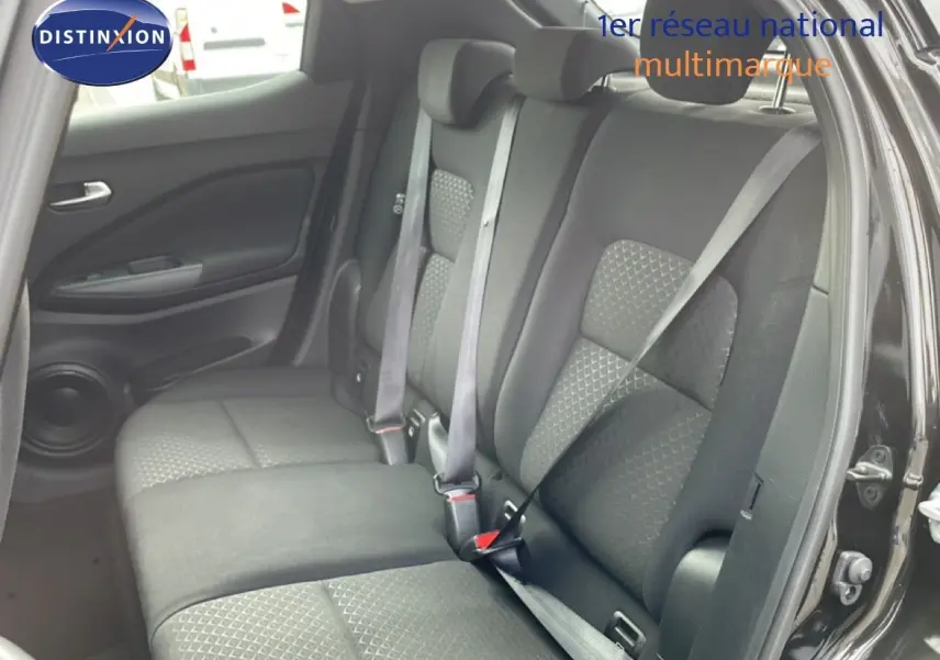 Vue intérieure montrant la banquette arrière en tissu gris noir du Nissan Juke 2023, porte arrière ouverte côté droit.