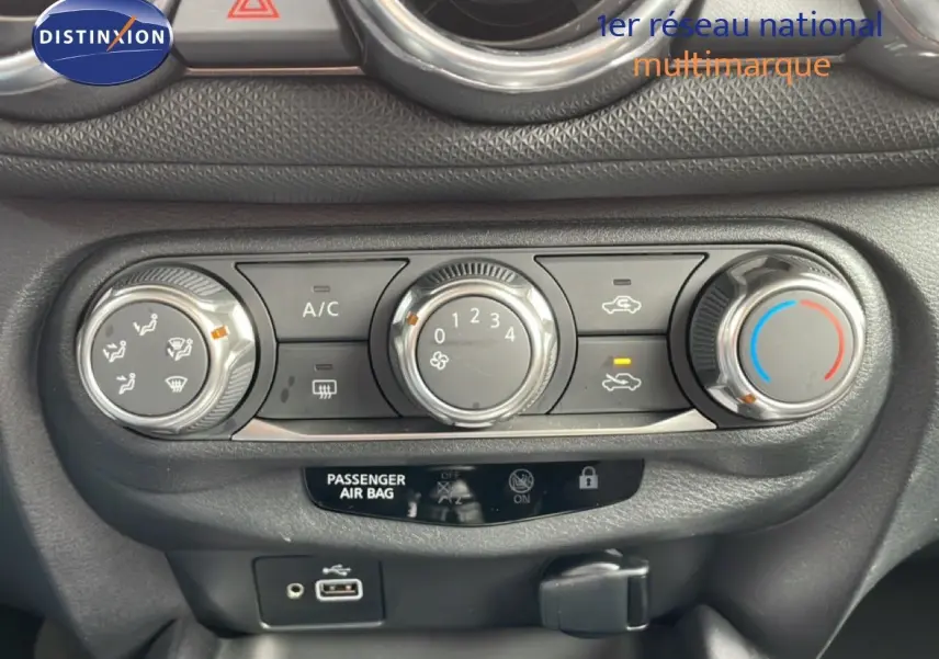 Vue rapprochée de la console centrale du Nissan Juke noir perle 2023, montrant les commandes de climatisation et connectiques USB.