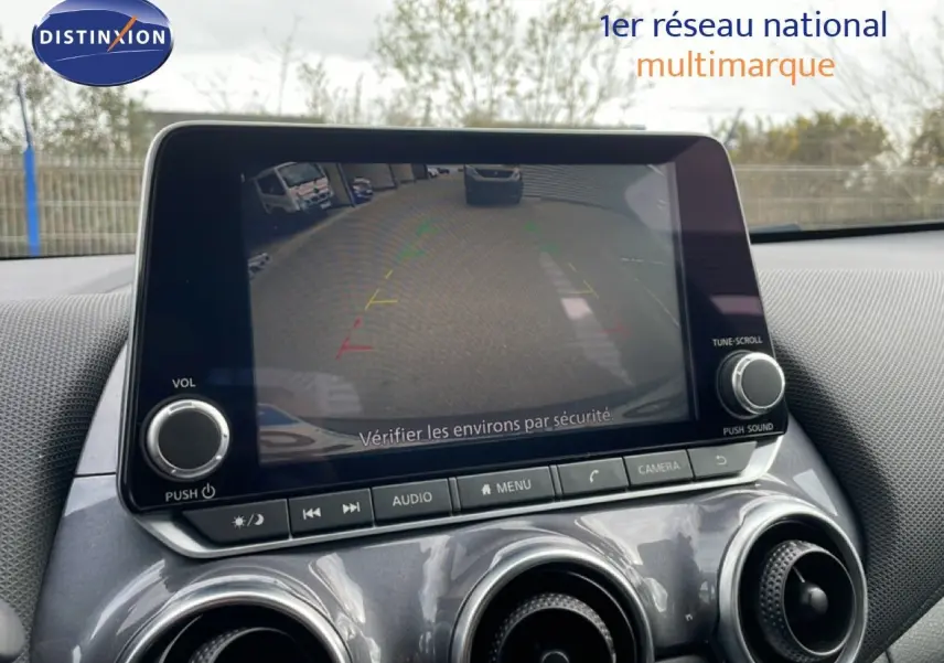 Écran central affichant la caméra de recul du Nissan Juke 2023, intérieur gris noir avec commandes audio et climatisation.