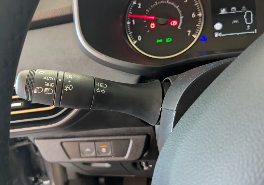 Gros plan sur la manette de commande des phares et clignotants du tableau de bord du Dacia Jogger gris schiste.