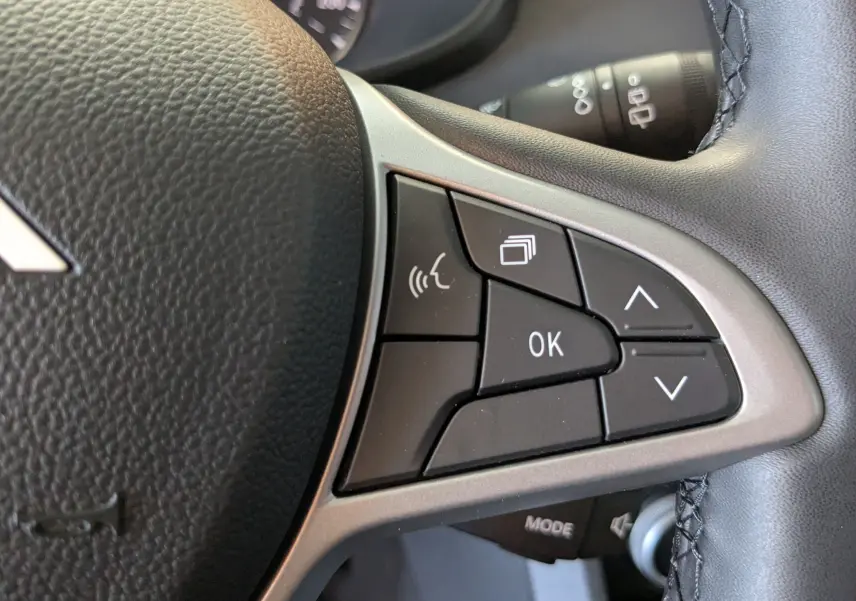 Gros plan sur les commandes multifonctions à droite du volant noir du Dacia Jogger 2026, boutons noirs avec marquages blancs.