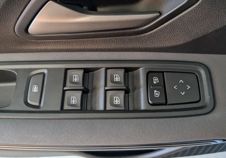 Gros plan sur les commandes des vitres et rétroviseurs sur la portière intérieure noire d'une Dacia Jogger 2026.