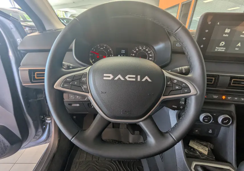 Vue rapprochée du volant noir de la Dacia Jogger 2026, avec tableau de bord et écran tactile visibles.