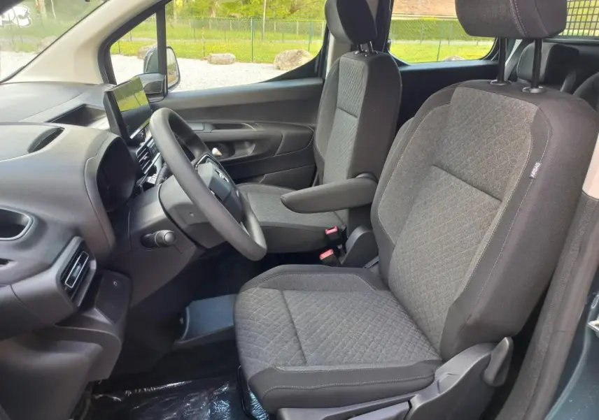 Vue intérieure côté conducteur de l’Opel Combo Life Elegance M 2025 bleu, sièges tissu gris avec accoudoir et écran tactile.
