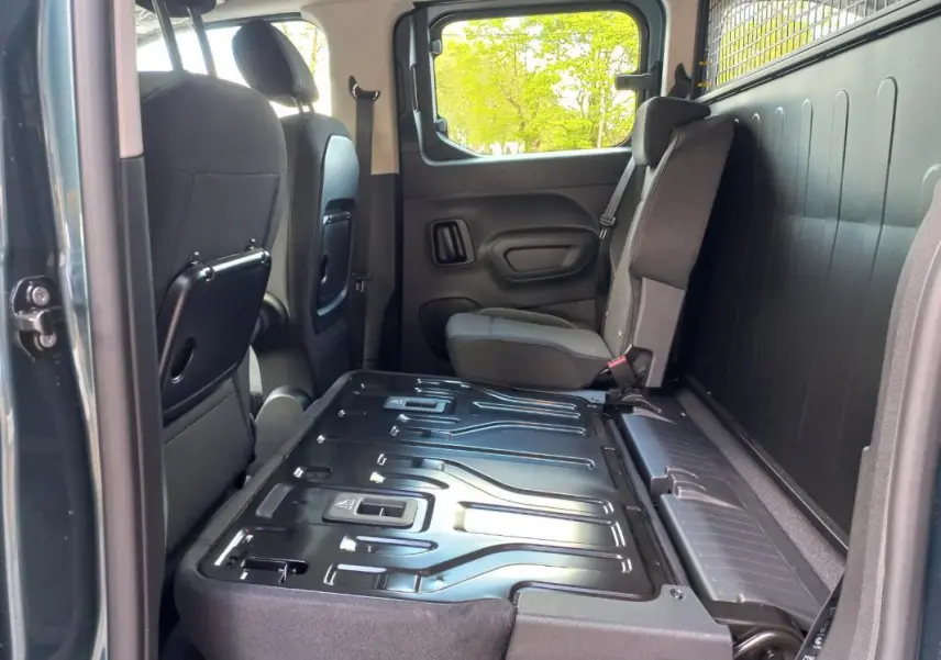 Vue intérieure côté droit de l’Opel Combo Life Elegance M 2025 bleu, montrant la banquette arrière rabattue et les sièges avant.