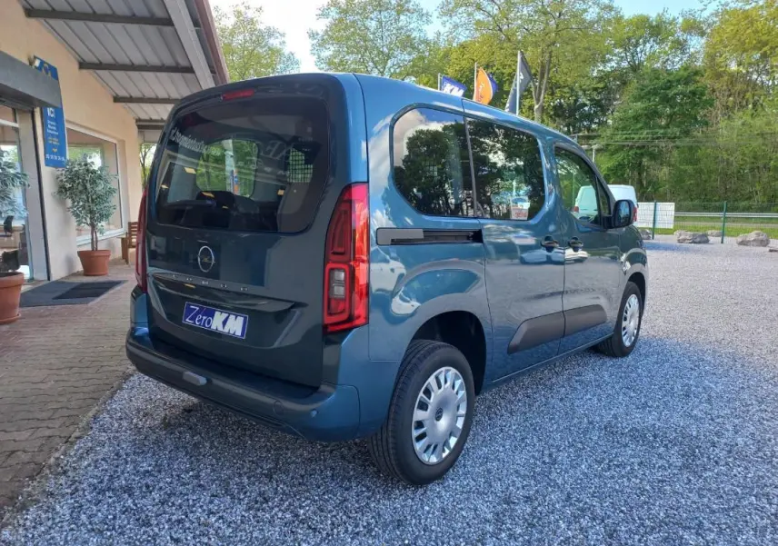 Vue 3/4 arrière droite d’un Opel Combo Life Elegance M bleu 2025, avec vitres teintées et logo Opel visible.