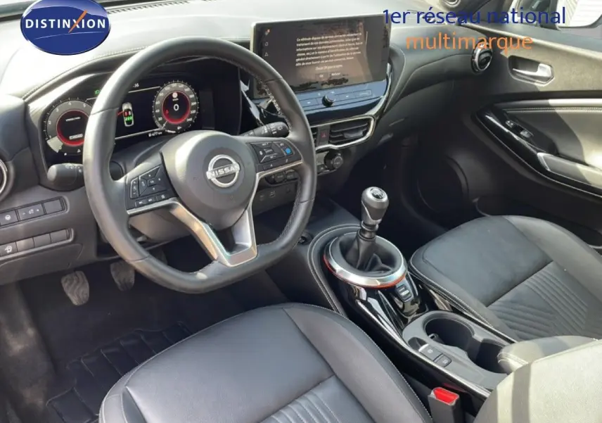 Vue intérieure côté conducteur du Nissan Juke 2025 noir Kuro Metal, volant cuir, boîte manuelle et écran tactile central.