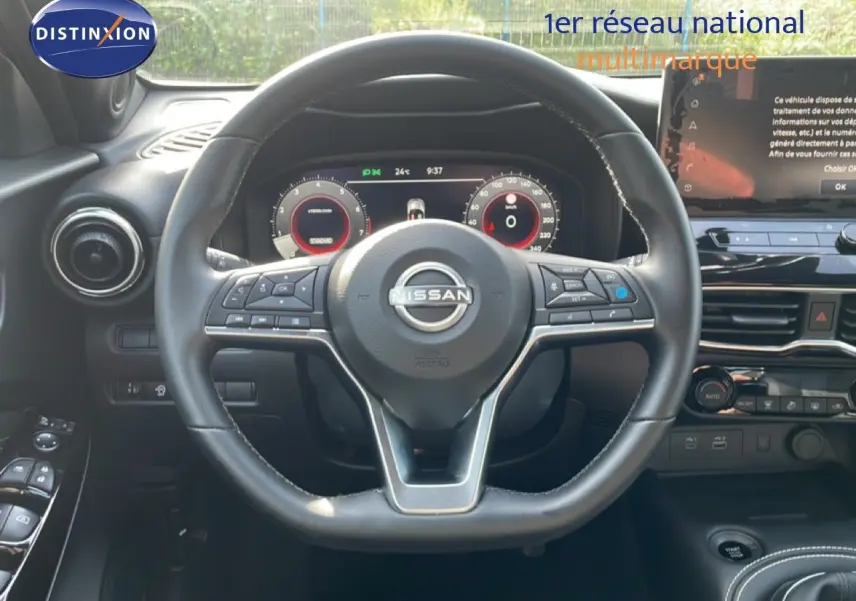 Vue intérieure centrée sur le volant cuir noir du Nissan Juke 2025, avec tableau de bord numérique et écran tactile visible.