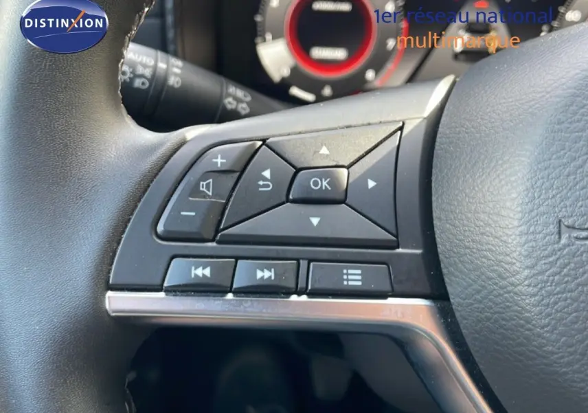 Gros plan sur les commandes au volant côté gauche du Nissan Juke 2025 noir Kuro Metal, avec tableau de bord partiellement visible.