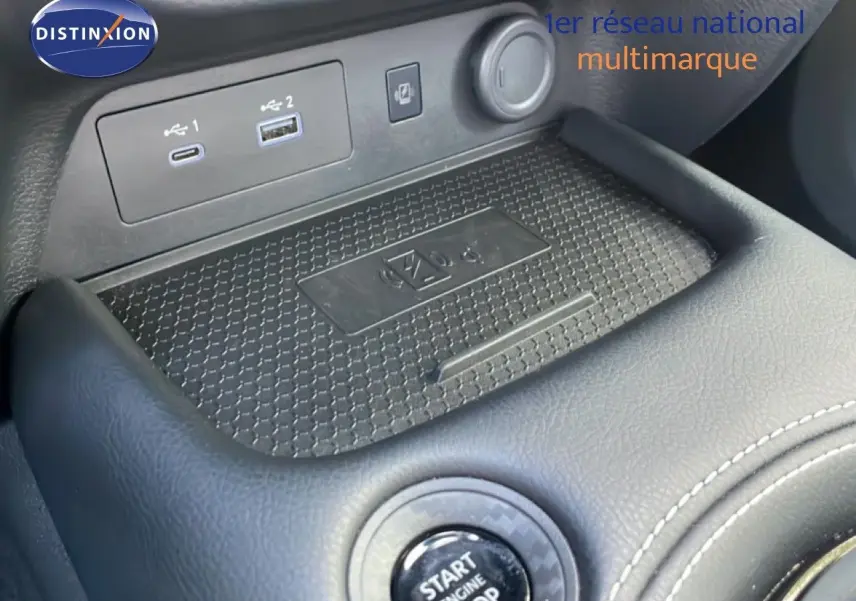 Gros plan sur la console centrale du Nissan Juke 2025 noir, montrant le bouton start/stop et les ports USB.