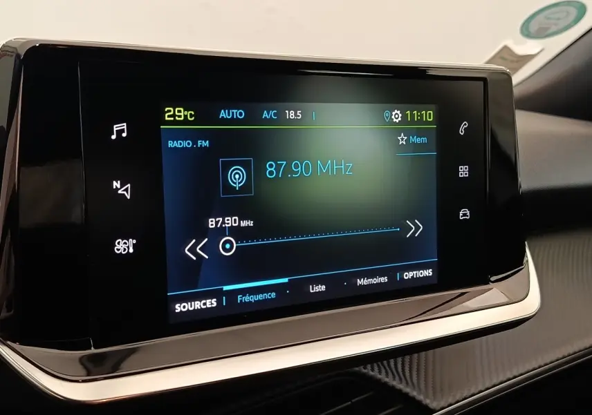 Écran tactile central du tableau de bord du Peugeot E-2008 électrique, affichant la radio FM à 87,90 MHz.