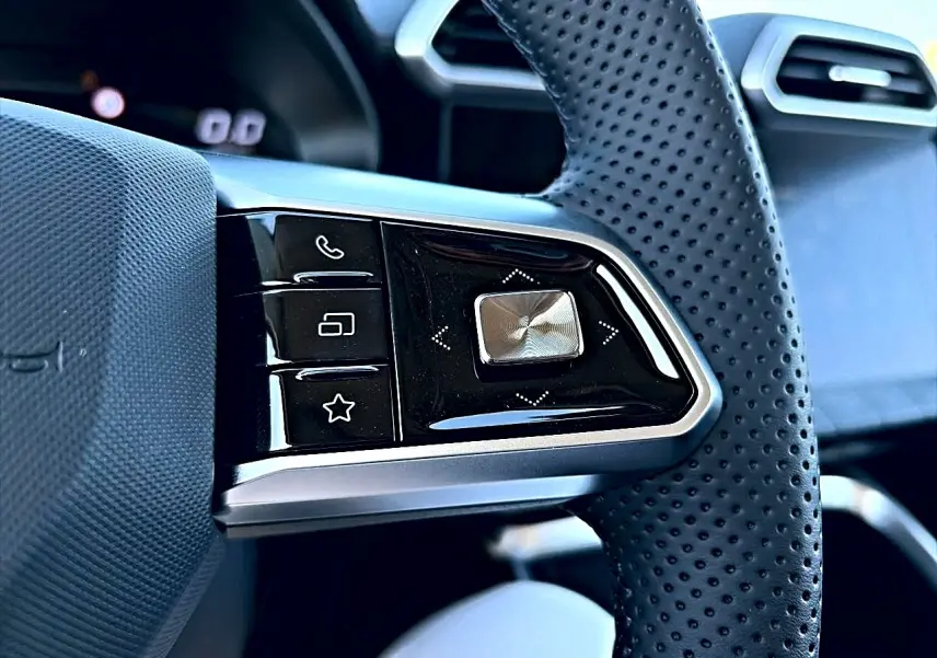 Gros plan sur les commandes noires et argentées du volant perforé côté gauche du MG Motor ZS hybride noir 2026.