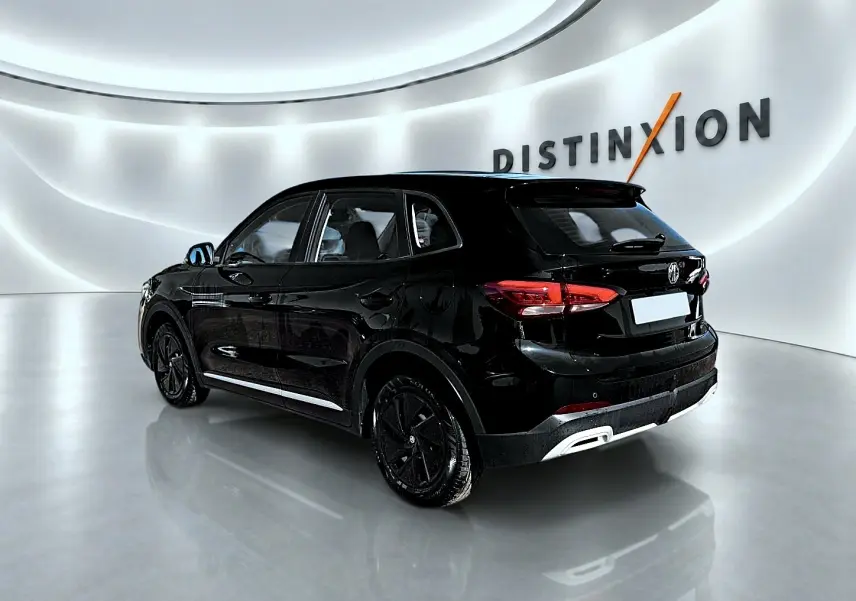 Vue 3/4 arrière droite du SUV MG ZS 1.5 hybrid noir brillant avec jantes noires dans un showroom moderne.