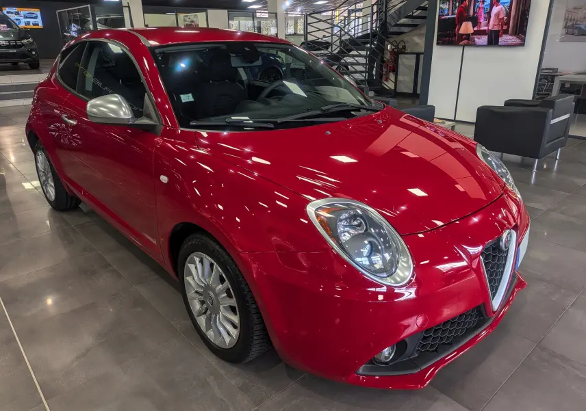 Vue 3/4 avant gauche de l'Alfa Romeo MiTo 1.3 JTDm rouge Alfa, avec jantes alliage et rétroviseurs argentés.