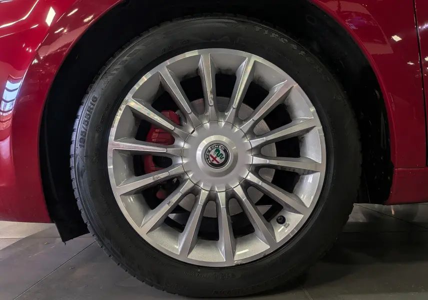 Gros plan sur la roue avant gauche rouge Alfa Romeo MiTo 1.3 JTDm avec jante alliage argentée et étrier de frein rouge.