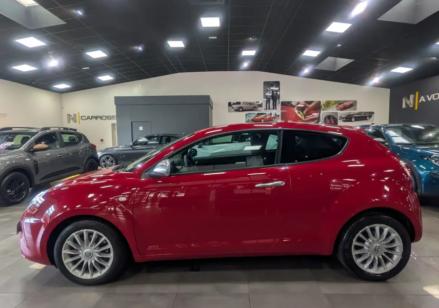 Profil latéral droit d'une Alfa Romeo MiTo rouge Alfa 2018, avec jantes alliage et vitres teintées en showroom.