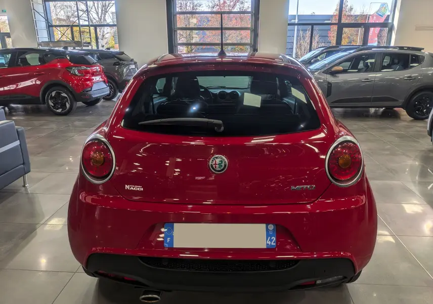 Vue arrière d'une Alfa Romeo MiTo rouge Alfa 2018 dans un showroom, avec logo et feux ronds caractéristiques.