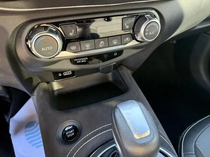 Gros plan sur la console centrale du Nissan Juke 2024 rouge Fuji, montrant les commandes de climatisation et le bouton start/stop.