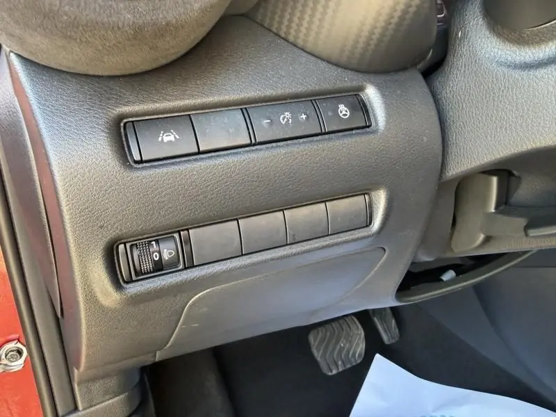 Détail du tableau de bord côté gauche du Nissan Juke 2024, montrant les commandes d'assistance et réglage des phares.