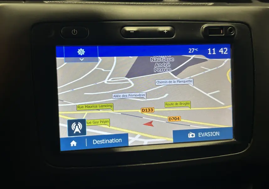 Écran GPS intégré du Dacia Duster noir, affichant une carte routière avec plusieurs noms de rues et options visibles.
