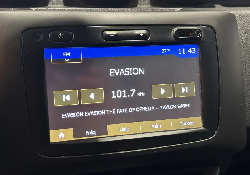 Écran tactile central du Dacia Duster noir 2018 affichant la radio FM sur la fréquence 101.7 MHz avec la chanson de Taylor Swift.