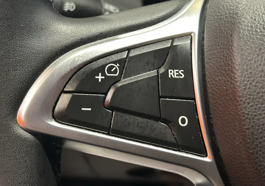 Gros plan sur les commandes noires du régulateur de vitesse au volant du Dacia Duster noir, finition Prestige 2018.