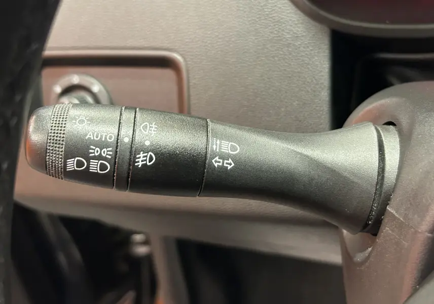 Gros plan sur la manette de commande des phares et clignotants dans l'habitacle du Dacia Duster noir 2018.