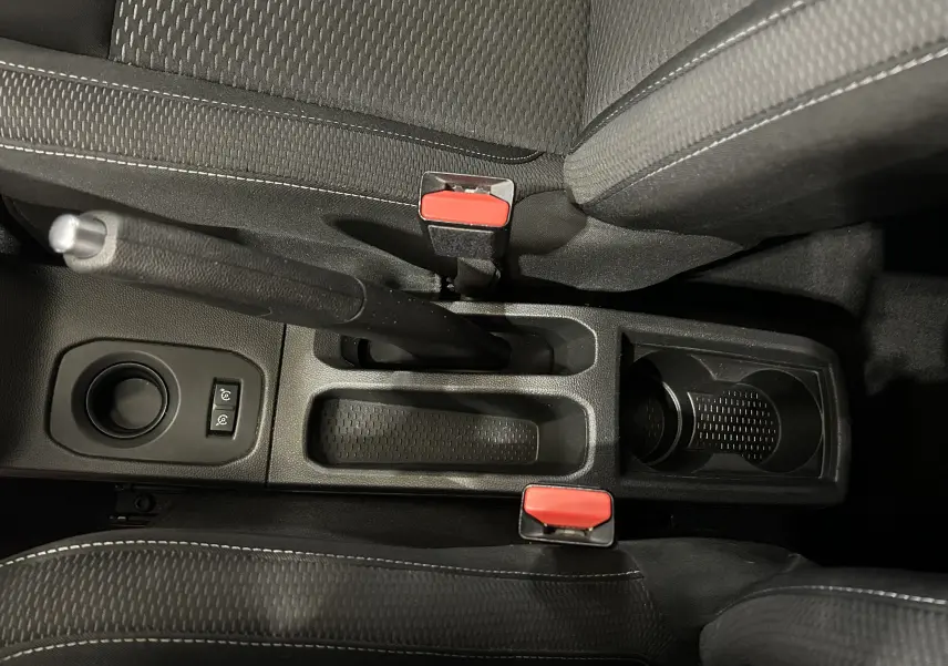 Vue plongeante sur la console centrale noire du Dacia Duster 2018, avec frein à main et deux ceintures rouges.