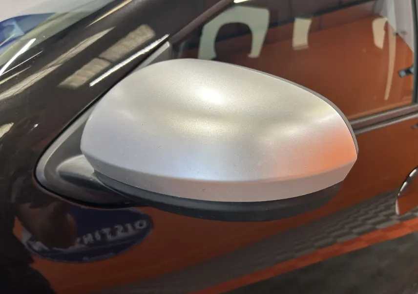 Rétroviseur extérieur argenté côté gauche sur Dacia Duster noir, vue rapprochée en léger angle.