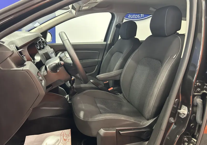 Vue intérieure côté conducteur du Dacia Duster noir 2018, mettant en valeur les sièges en tissu et le tableau de bord simple.